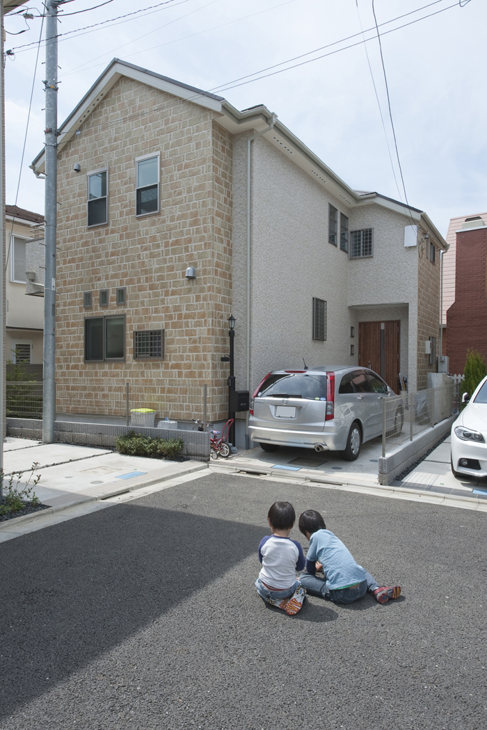 温かみのある可愛らしい外観と私道で遊ぶ子供達